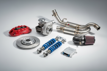 Audi performance parts including turbocharger, brake caliper, exhaust, air filter, and coilovers on white background