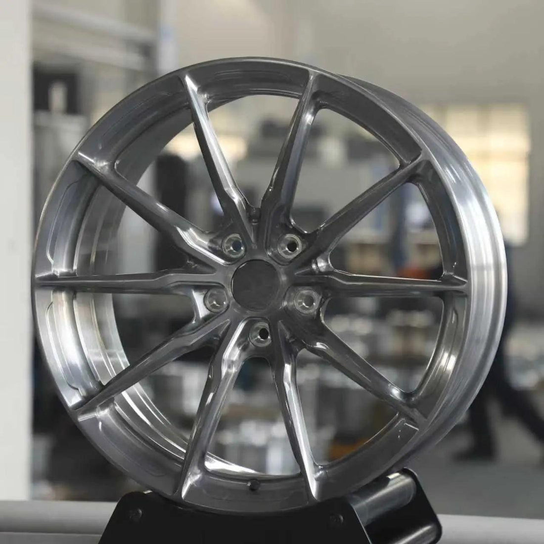 Glossy silver alloy wheel for Audi, ten-spoke design, displayed indoors