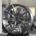 Glossy silver alloy wheel for Audi, ten-spoke design, displayed indoors