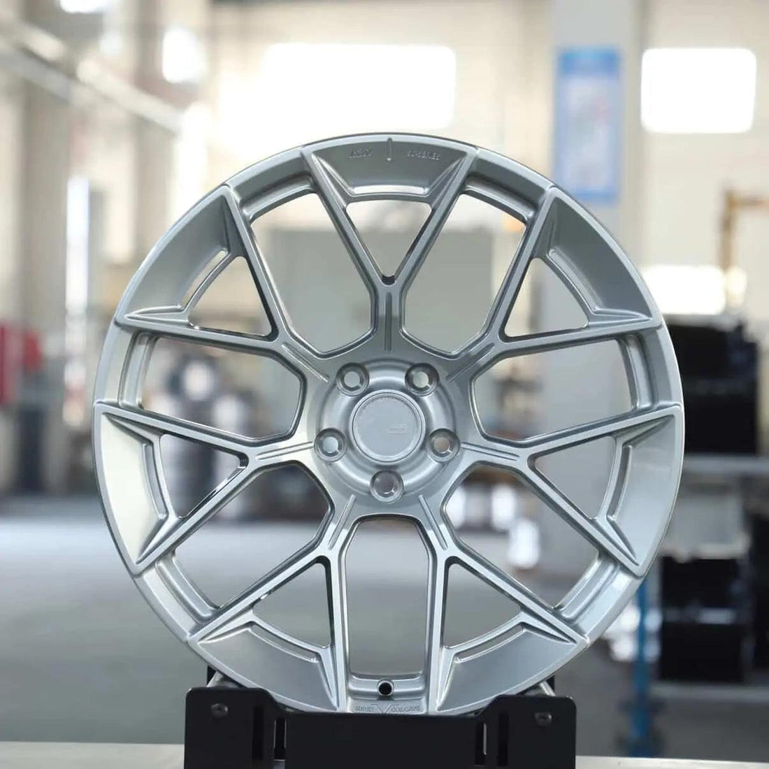 Silver multi-spoke alloy wheel for Audi performance cars in a workshop setting.