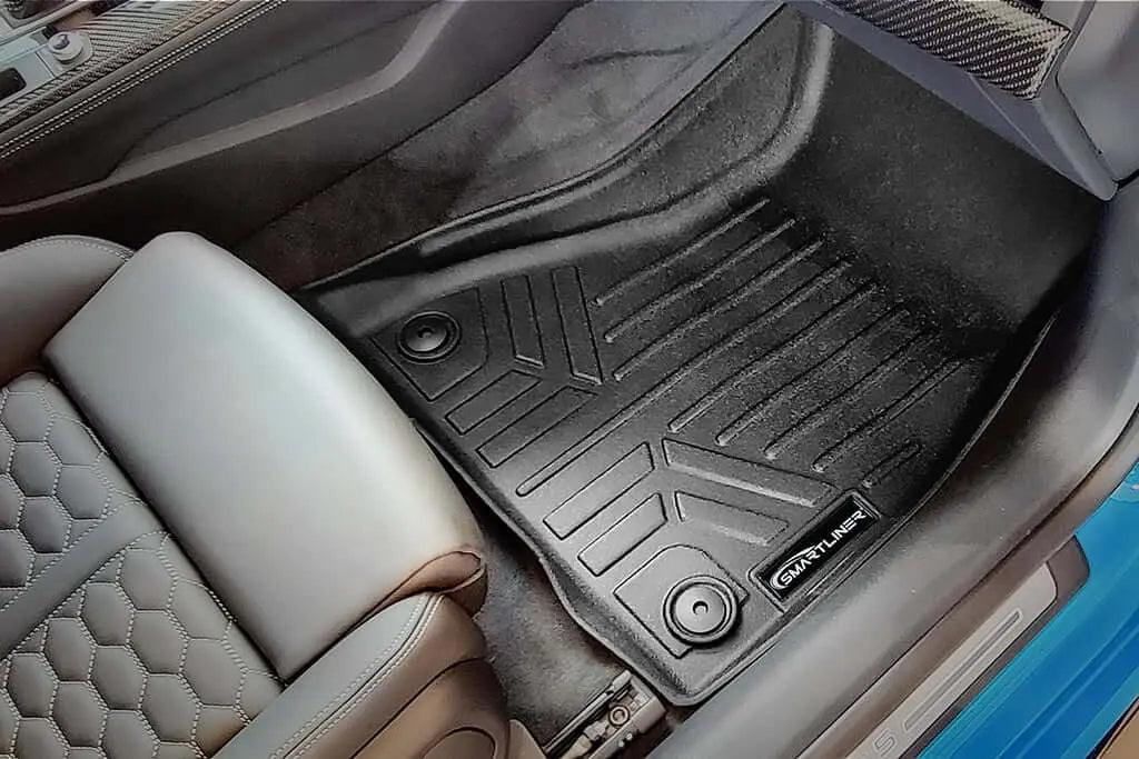 Custom-fit black rubber floor mat in Audi front passenger footwell, textured seat visible