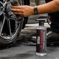 Person cleaning car wheel with microfiber towel and Le Mans wheel cleaner spray bottle