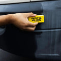 Hand using yellow Wash & Whips cleaning tool on car bumper for detailing