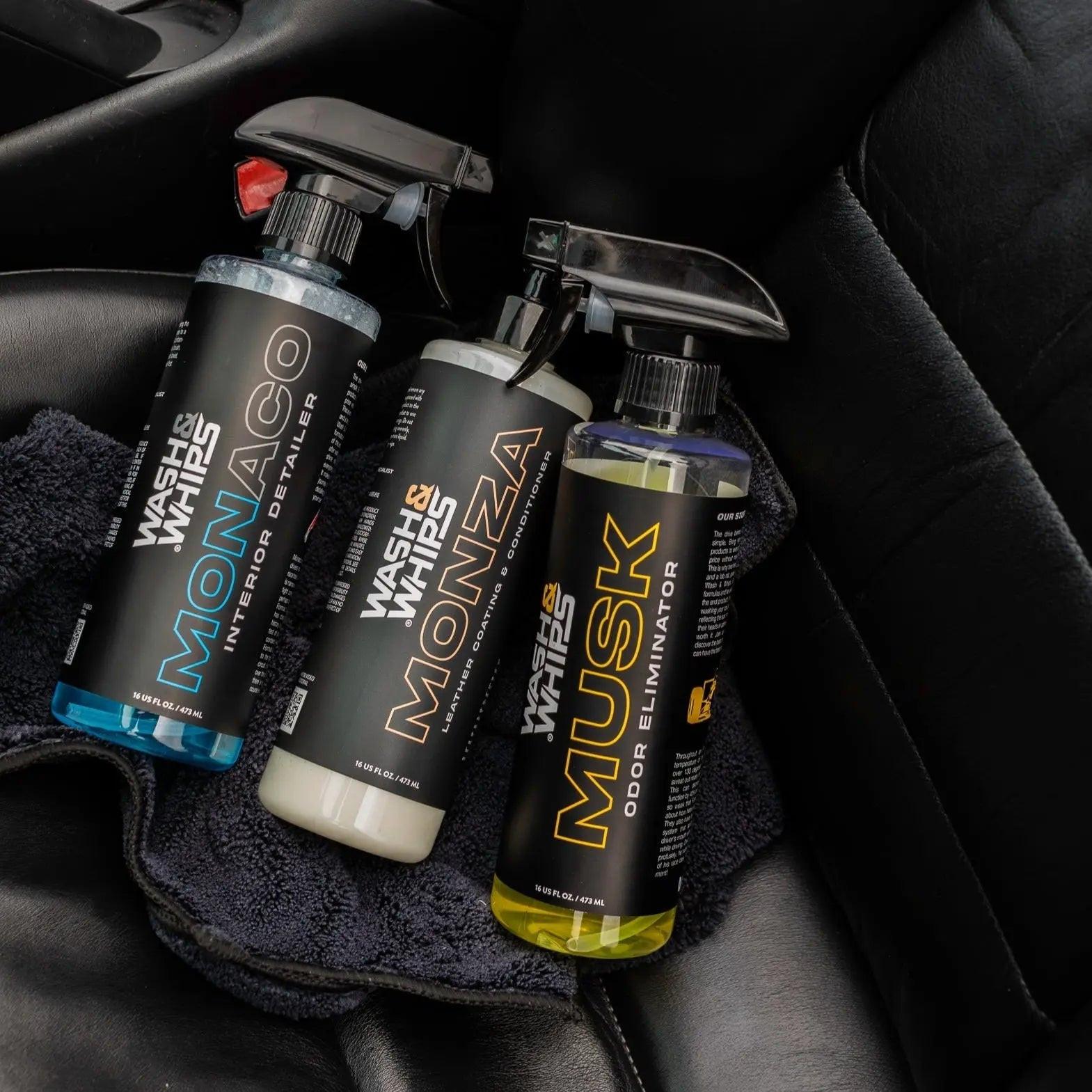 Car interior with three Wash & Whips detailing products on black leather seat.