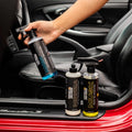Hand holding Monza interior sealer bottle beside Monza and Musk car care products on car seat