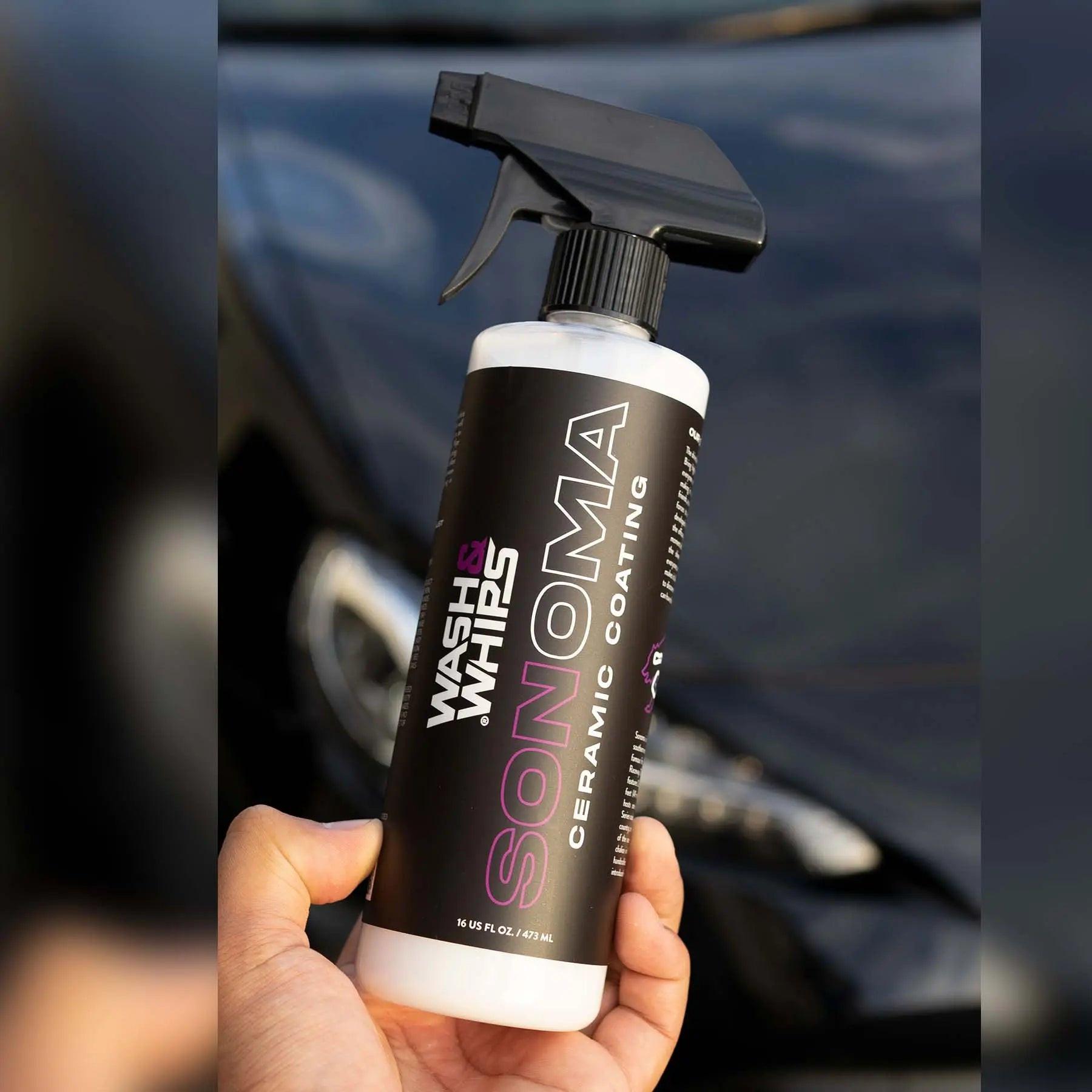 Hand holding Wash & Whips Sonoma ceramic coating spray bottle in front of a car