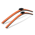 Pair of orange aerodynamic car wiper blades with black mounting clips on white background