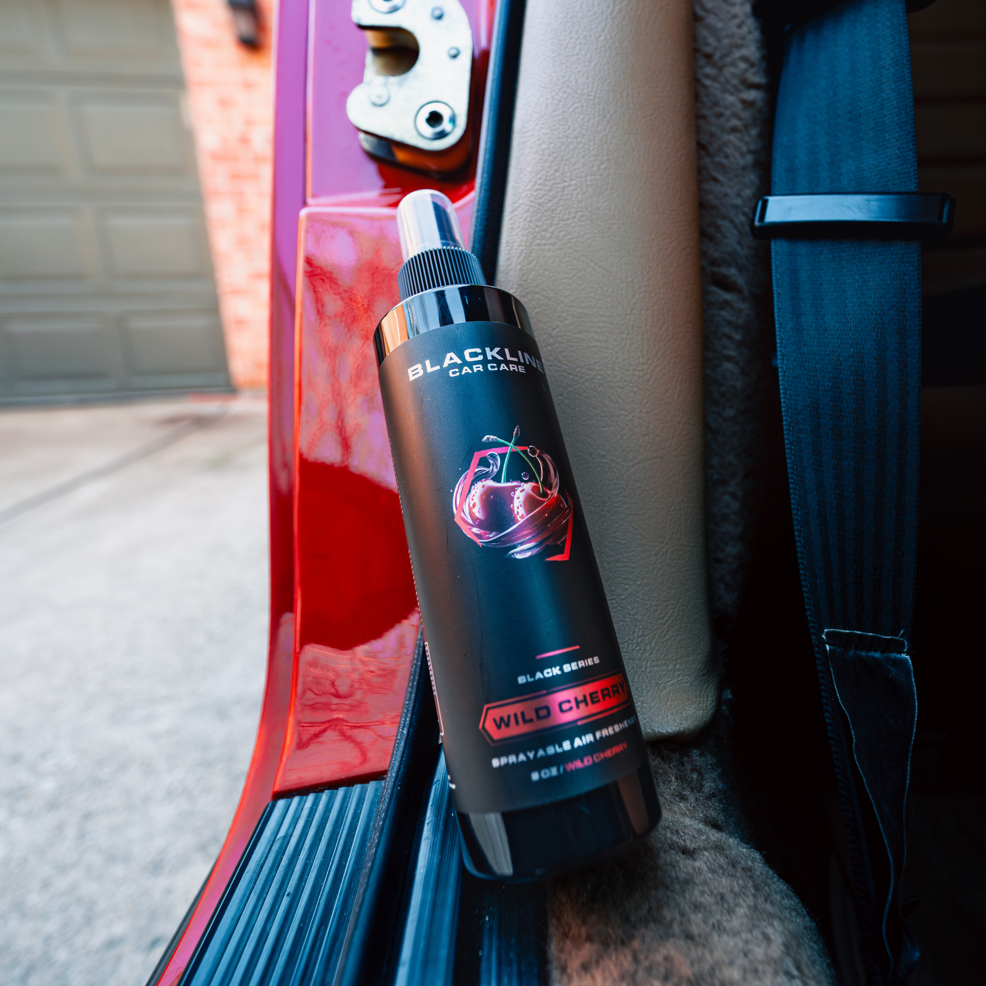 Blackline Car Care 8oz Wild Cherry car air freshener hanging from a vehicle's interior for fresh scent.
