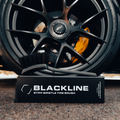 Blackline Car Care stiff bristle tire brush with durable handle for cleaning vehicle tires and wheels.