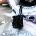 Blackline Car Care stiff bristle tire brush with sturdy handle for cleaning vehicle tires and wheels.