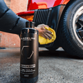 Blackline Car Care BLACKLINE® Blackout Trim & Tire Dressing spray applied to car tires and trim for a sleek, shiny finish.