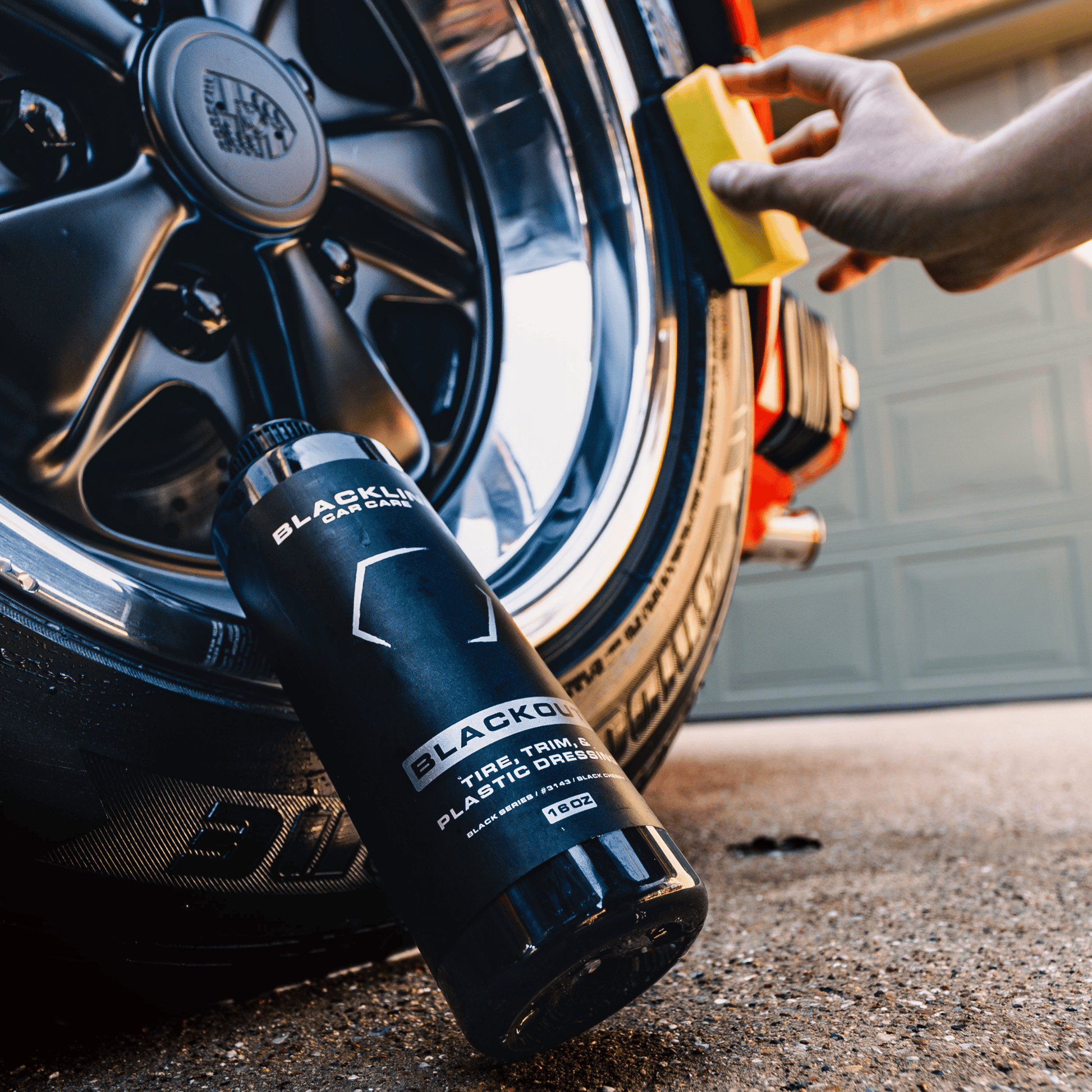 Blackline Car Care BLACKLINE® Blackout Trim and Tire Dressing spray applied to car trim and tires for a sleek, shiny finish.
