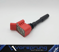 Red and black performance ignition coil for Audi, featuring a branded metal plate and sleek design.