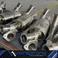 Stainless steel sport downpipes for Audi Q7 3.0T displayed on a workshop table