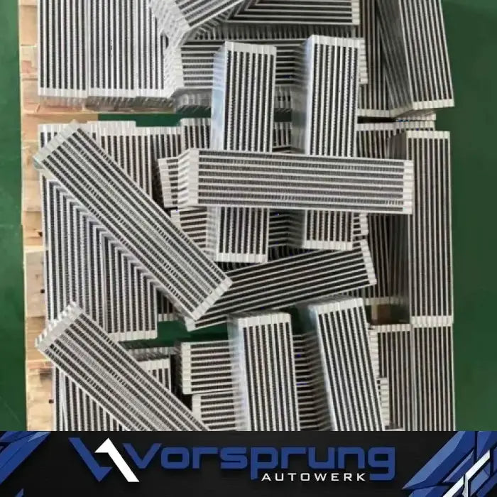 Stack of rectangular metal heat exchanger components with fins, Vorsprung Autowerk branding visible.