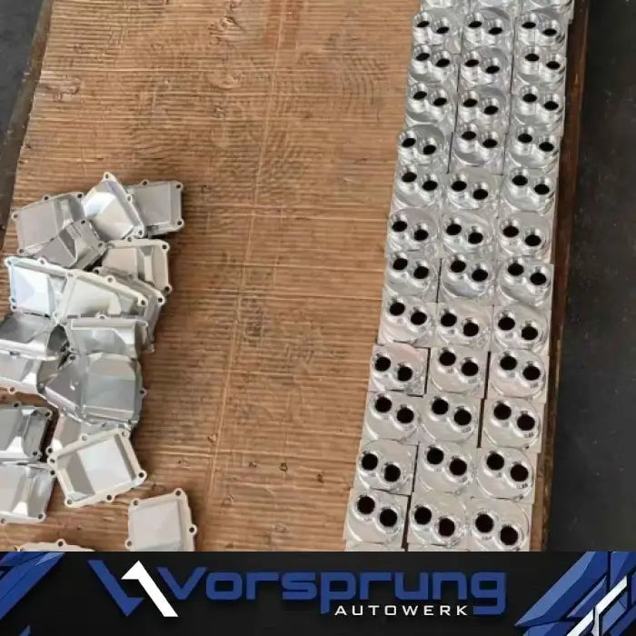 Set of machined aluminum engine parts for Audi 3.0T V6, EA837, arranged on a wooden surface.