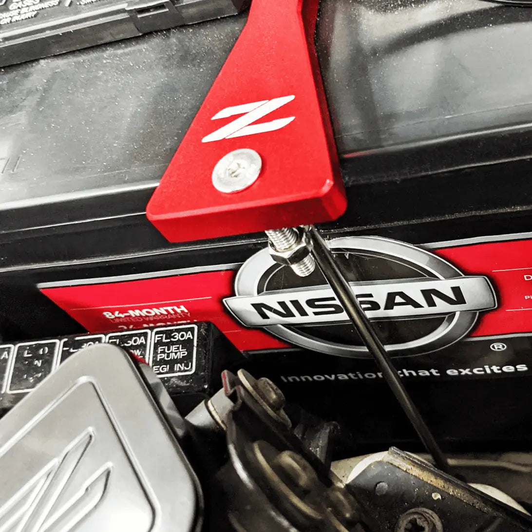 ZSPEC billet battery hold down bracket installed on a Nissan Z32 300ZX, with stainless hardware securing the battery in place.